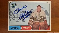 Front of Charlie Hodge hockey card with autograph in blue ink, showing player in goal for Oakland.