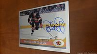 Signed Daniel Alfredsson hockey card showing him skating, with blue ink signature on front.