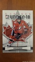 Front of the Drew Doughty 2007 Under-18 hockey card showing player skating in Team Canada red jersey with autograph overlaid