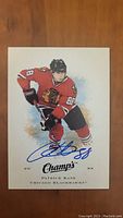 Front of Patrick Kane autographed hockey card showing player in red Chicago Blackhawks uniform with blue autograph across the front.