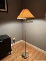 Full view of lamp in corner showing base, stem, swing arm and shade
