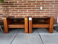 Pair of teak and smoked glass end tables from front angle showing wood frame and lower shelf.