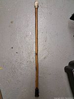 Full view of the entire wooden walking stick showing straight shaft with slight bends and rubber tip.