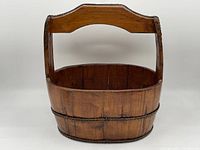 Front view of the antique wooden bucket with carved handle showing its shape and construction.