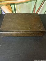 Closed wooden case holding flatware set showing exterior top with some surface wear marks