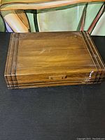 Closed wooden case with visible surface scratches and light wear on a flat surface