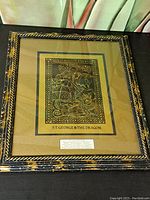 Framed vintage print with black and gold frame and gold matting showing St. George slaying the dragon in a detailed medieval style.