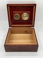 Open cedar wood humidor showing interior lined with cedar and inset brass-trimmed glass hygrometer and vent.