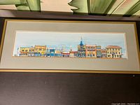 Frontal view of framed watercolor painting showing the detailed panoramic buildings of Old Strathcona, Edmonton, with a wooden frame and beige gold-trimmed matting.