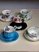 Photo showing all five cup and saucer sets with distinct floral and month name designs