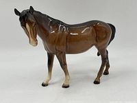 Side photo of vintage brown and black porcelain horse figurine showing detailed craftsmanship and glossy finish