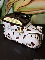 Front-side angle view of the ceramic cookie jar shaped like a vintage Humane Dog Catcher truck with dog figure at window.