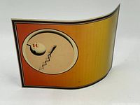 Front view of the unique postmodern clock with orange gradient background and circular face with inset window.