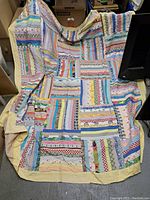 Full view of vintage patchwork baking apron with colorful fabric strips arranged horizontally and bordered in solid light yellow fabric.