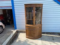 Front view of the vintage Drexel wooden corner cabinet showing curved glass doors and wood finish.