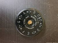 Top view of the black circular instrument showing musical notes A to G with sharps and flats around the perimeter, and 'Chromatic Pitch Inst Master Key' text.