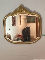 Front view of beveled glass mirror with painted wood frame and carved ornamental top.