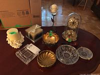Overview of coffee table top with anniversary clock, glass and metal bowls, glass ashtrays, and candles.