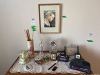 Lot showing all items on lace cloth under a framed print on the wall
