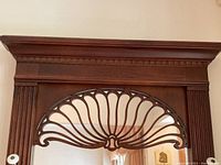 Close-up of wooden carved fan design above hooks on hall stand