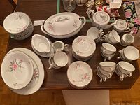 Overview of the full china set including cups, saucers, tureen, gravy boat and plates, showing floral pattern detail and condition