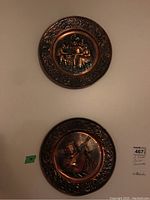 Pair of embossed decorative copper plates with musical scenes and ornate borders