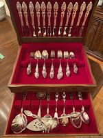 Full view of the flatware set in wooden case showing various pieces including knives, forks, spoons and serving utensils.