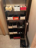 Full view of shelving unit containing 12 pairs of women's shoes and boots in shoeboxes in worn condition.