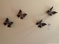 Four steel butterflies arranged on a flat surface showing various colors and details.