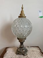 Pair of vintage tabletop lamps with textured glass globe shades and ornate brass bases on a crocheted lace cloth.
