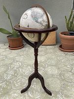 Front view of the 12 inch diameter Replogle globe mounted on wooden tripod stand outdoors.