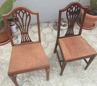 Front view of two wooden dining chairs with butterfly back design showing overall condition and natural finish.