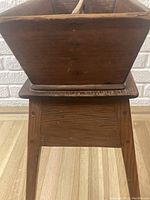 Side view of the wooden compartmentalized tray showing the wood grain and repair evidence on the base and legs.