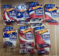 Top view of 10 packaged Hot Wheels Stars & Stripes toy cars arranged on floor.
