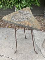 Triangular Nautilus sculpture on rusty iron stand outdoors on concrete. Seen from above to show Nautilus pattern.