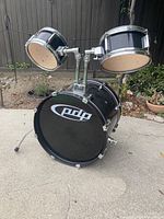 Photo of black PDP brand 18 inch bass drum with 10 inch and 8 inch tom drums mounted on top, showing the assembled drum kit section.