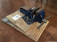 Three blue 3-inch bench vices mounted on a wooden board showing side angle view.