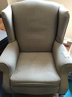 Front view of the beige wing back chair showing upholstery and overall shape.