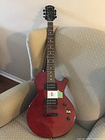 Full front view of cherry red Epiphone electric guitar on chair