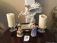 Photo of vintage A. Belcari Pegasus marble statue on wooden base with two glass candle holders and two ceramic figurines arranged around it.