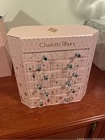 Front view of the pink Charlotte Tilbury storage chest with 12 drawers, decorated with celestial motifs and the brand name on top.