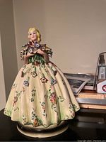Front view of porcelain figurine showing delicate lady with bouquet and floral-patterned gown