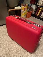 Front view of retro red American Tourister suitcase showing hard shell textured exterior and top handle.