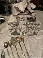Overview of all flatware pieces and serving utensils displayed on protective paper