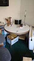 Wide view of the round table with items on top, showing overall condition and structure.