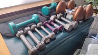 Overview photo of various dumbbells arranged on a padded surface.