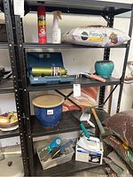 Full view of the black metal rack stocked with gardening supplies, tools, and pots; showing the size and usage condition.