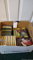Box filled with multiple Nancy Drew hardback books with yellow spines and two visible front covers including 'The Haunted Showboat' and 'Nancy Drew and the Mysterious Letter'.