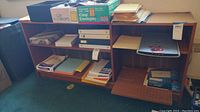 Shelves filled with binders, paper stacks, boxes of envelopes, and a wooden cutting board on bottom shelf