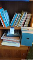 Shelf with vintage children's books including the 'Land of Oz' book and a mix of hardcover and paperback children's literature.